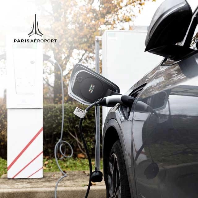 A car connected to an electric terminal in a Paris Airport parking lot