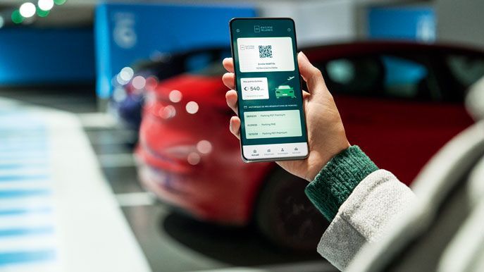 A person shows his Extime Rewards loyalty card on his phone in an official Paris Aeroport parking lot