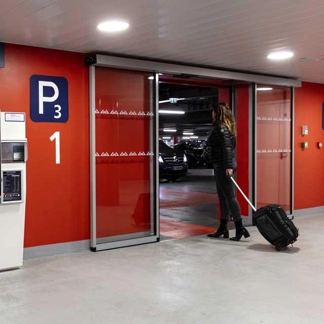 A woman with a cabin suitcase heads for the official Paris Aeroport parking lot